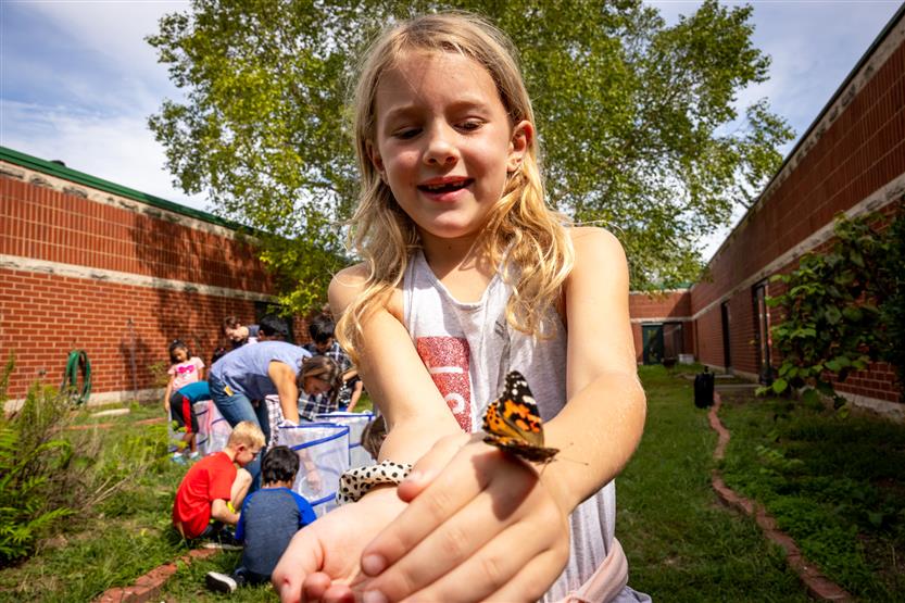 A girl holds out a butterfly